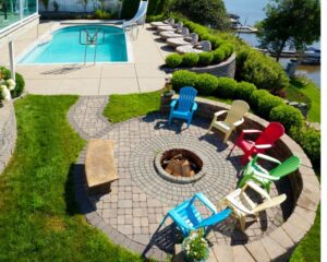 An aerial view of a backyard with a fire pit and pool surrounded by concrete pavers.