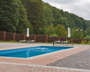 A stamped concrete swimming pool nestled in a wooded area.