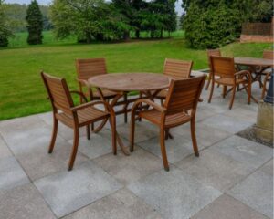 A wooden table and chairs in a grassy area with Stamped Concrete.