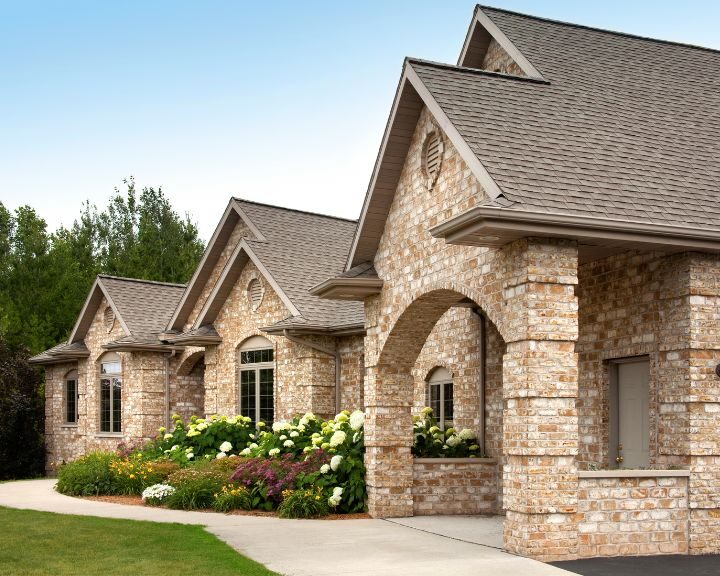 A city home featuring a stone exterior and concrete slabs landscaping.