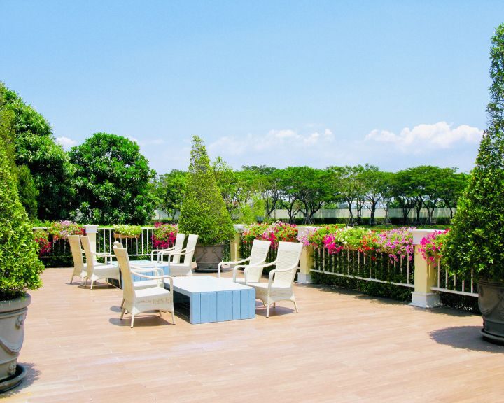 A city balcony adorned with a table, chairs, and potted plants.